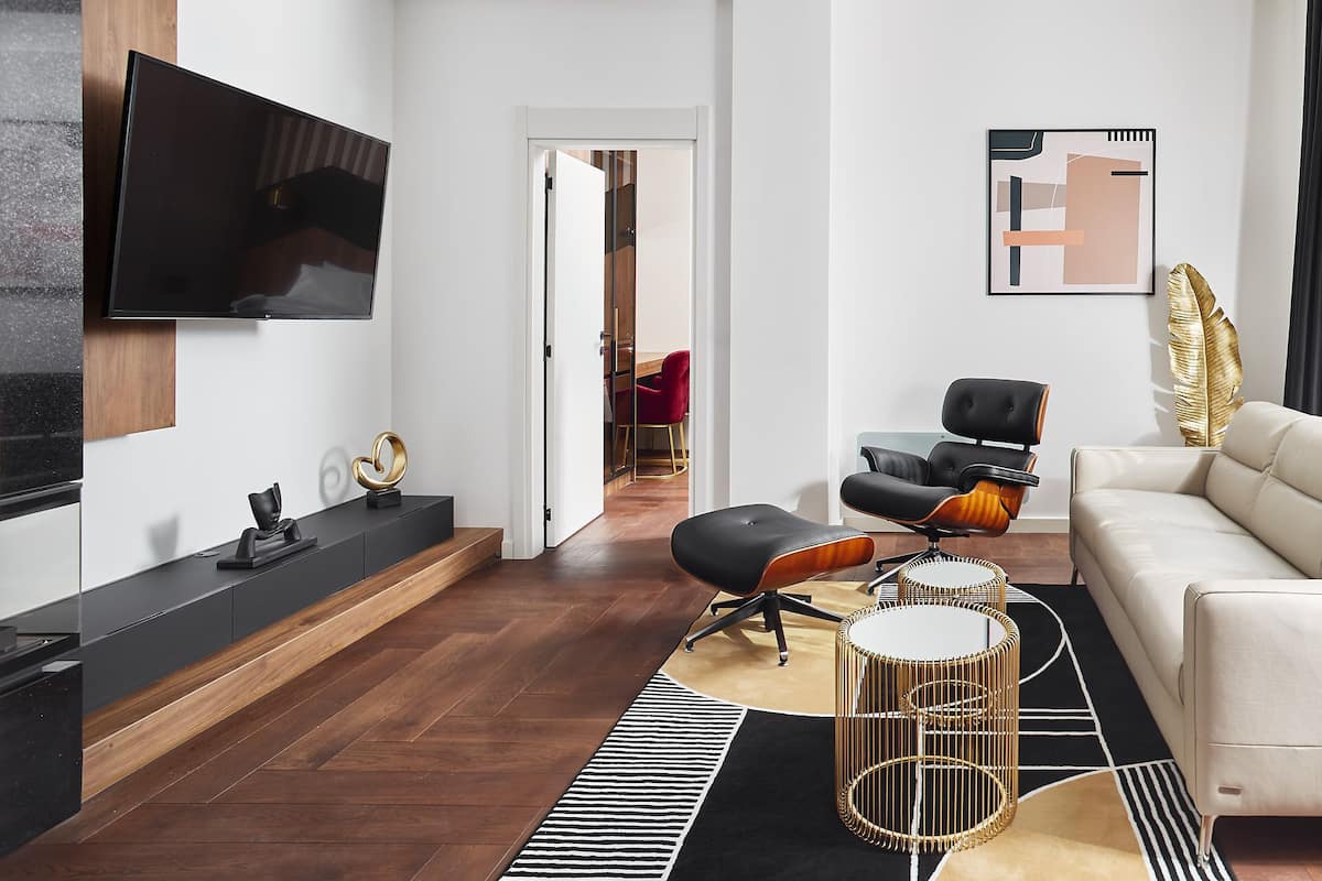 A modern living room with a flat-screen TV, a sofa, a chair, a coffee table, and a decorative wall piece.