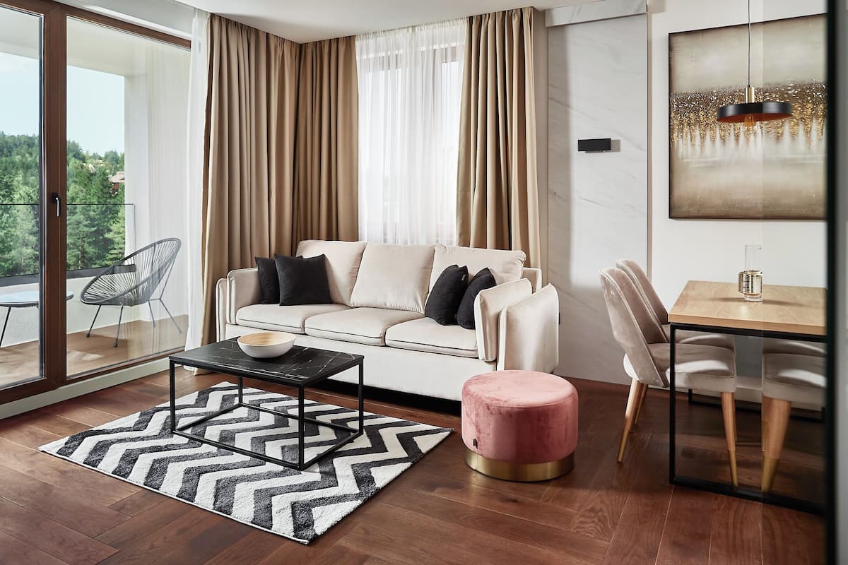 A modern living room with a sofa, coffee table, ottoman, and dining area.