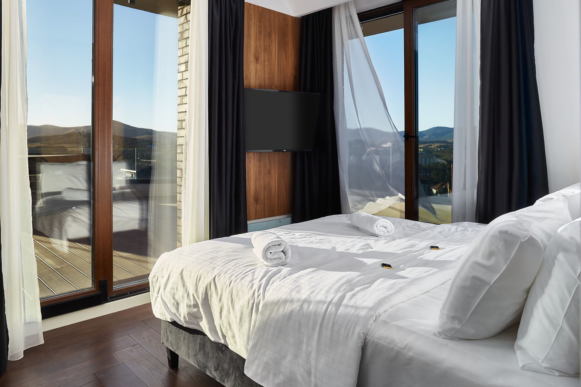 Ett hotellrum med en stor säng, en TV och utsikt över bergen.