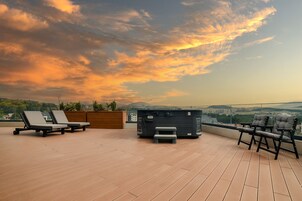 A rooftop terrace with lounge chairs, a hot tub, and a view of the cityscape.