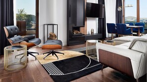 Een moderne woonkamer met een open haard, leren banken, een eethoek en een groot raam met uitzicht over de stad.