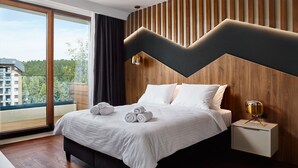 Een moderne hotelkamer met een groot bed, een nachtkastje en uitzicht op groen.