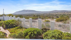 A fenced garden with a clear view of a distant mountain range. - Bona View G36 (Cape Town)