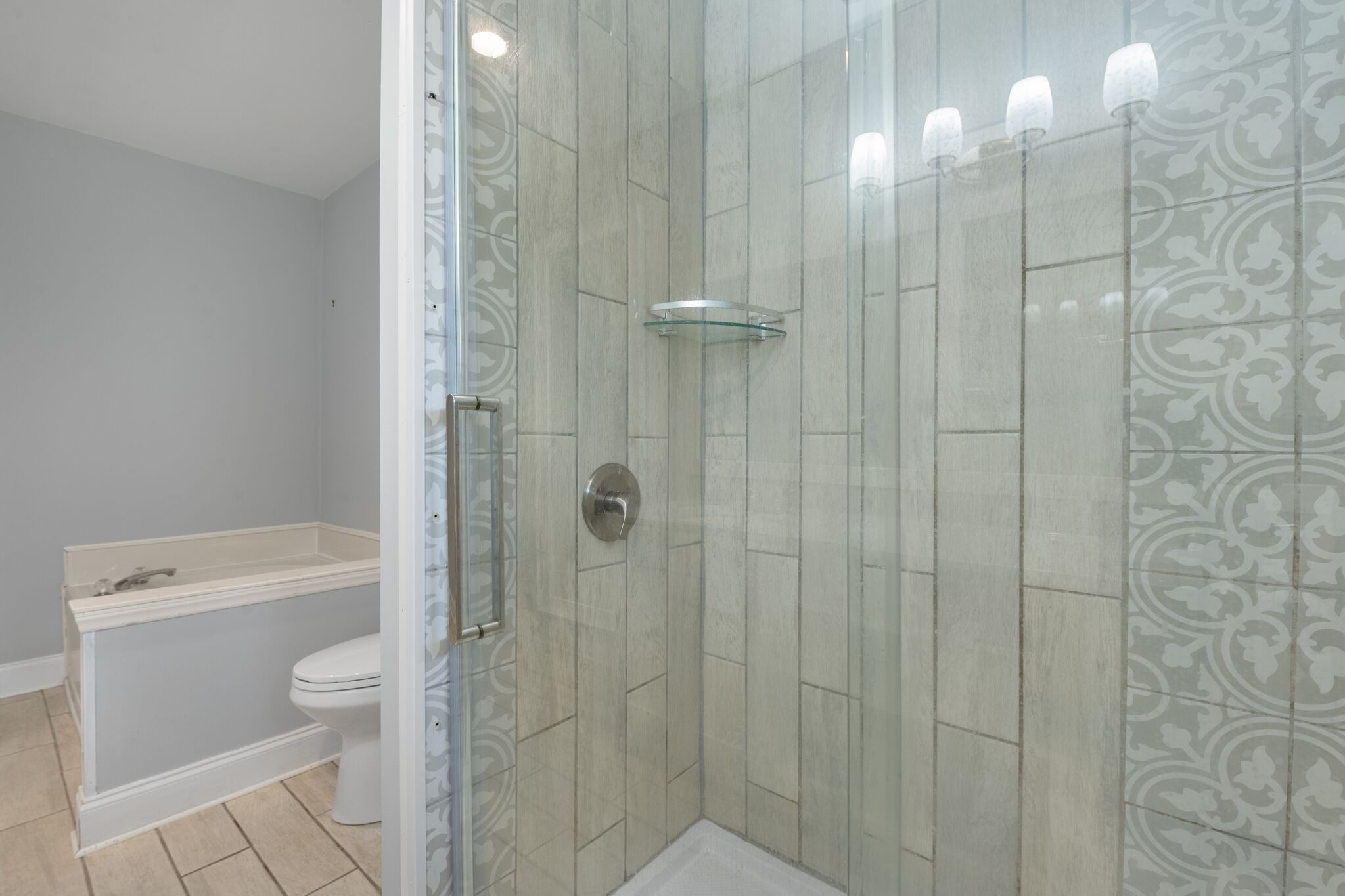 A bathroom with a glass-enclosed shower, a toilet, and a bathtub.