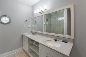 A bathroom with two sinks, a large mirror, and a round window. - Spoon Haven: Village at Nags Head | Sound Access (Nags Head)