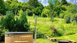 A hot tub in a lush garden with a wooden deck and a metal pole. - Rudnik Krc070 in Rudn k (Rudník)