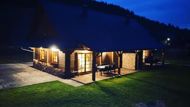 A cozy cabin with a thatched roof, wooden exterior, and a well-lit patio area with outdoor seating. - Velk Karlovice Mkr545 (Velké Karlovice)