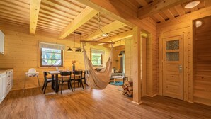 A wooden cabin interior with a dining area, a hammock, and a view of the outdoors. - Velk Karlovice Mkr545 (Velké Karlovice)