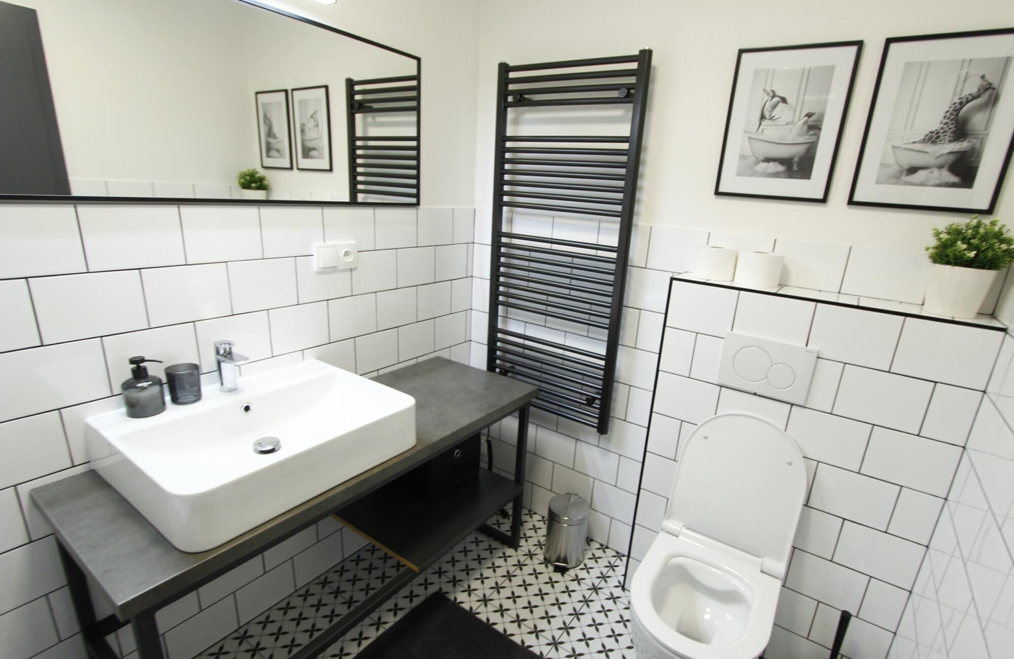 A modern bathroom with a white sink, black towel rack, and a toilet.