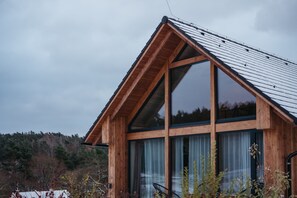A modern wooden cabin with large windows and a sloped roof.