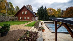 A rustic wooden house with a stone wall, a paved driveway, and a solar panel array. - Vysoke nad Jizerou Kkh070 (Vysoké nad Jizerou)