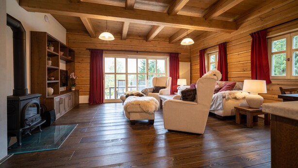 A cozy log cabin interior with a fireplace, wooden floors, and a seating area with a sofa and chairs. - Vysoke nad Jizerou Kkh070 (Vysoké nad Jizerou)