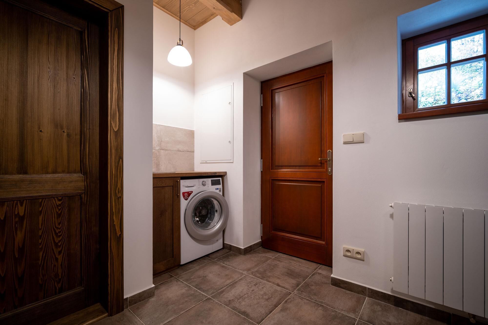 Un cuarto de lavandería con lavadora, una puerta de madera y una ventana con vistas.