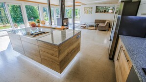 Una cocina moderna con una isla grande, armarios de madera y vista al exterior.