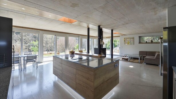 Una cocina moderna con una isla central, ventanas amplias y un diseño minimalista.