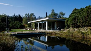 Una casa moderna con piscina, rodeada de árboles y un cielo despejado.