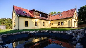 A large, yellow building with a red roof and a pond in the foreground. - Luxe Villa in Bernartice Kkh045 (Bernartice)