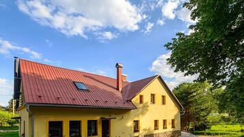 A yellow building with a red roof, a chimney, and a small window.
