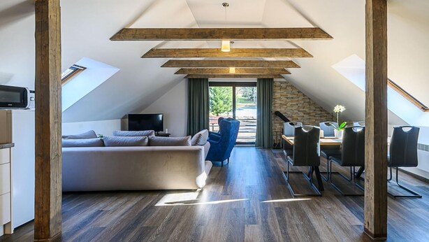 A modern loft-style living space with a sloped ceiling, a sofa, a dining area, and a view of the outdoors. - Luxe Villa in Bernartice Kkh045 (Bernartice)