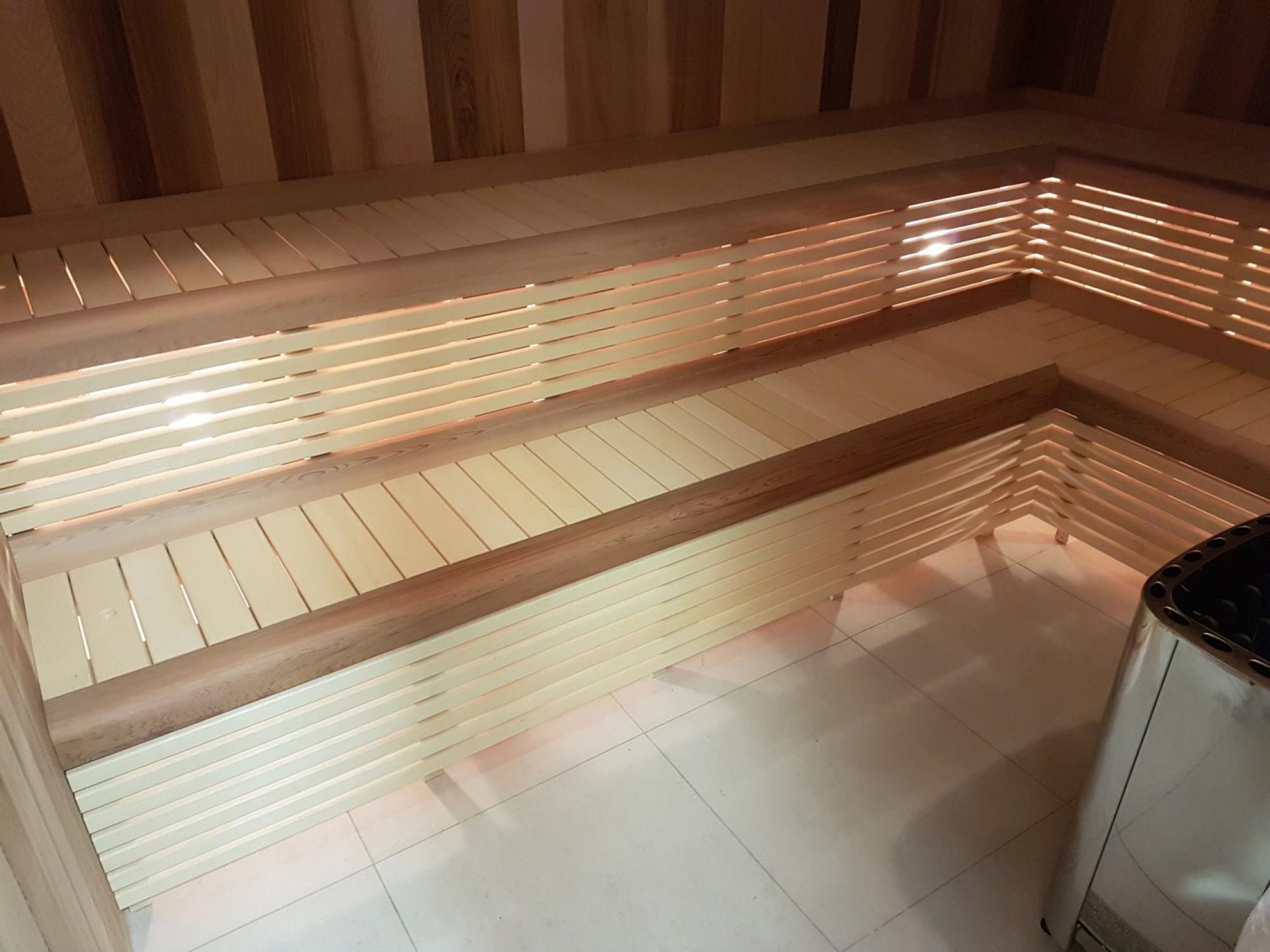 A modern, well-lit room with a wooden bench and a trash bin.