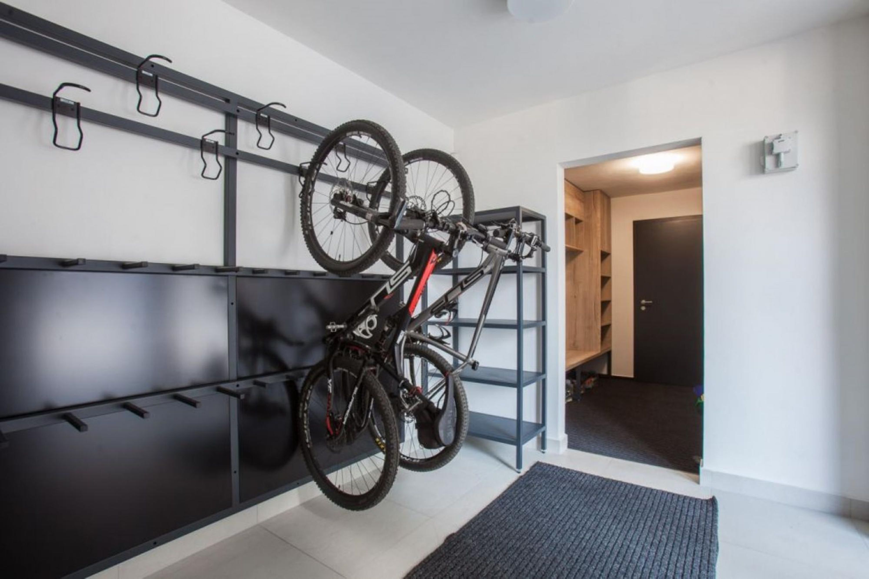 A bike rack with two bicycles, a wooden door, and a black mat.