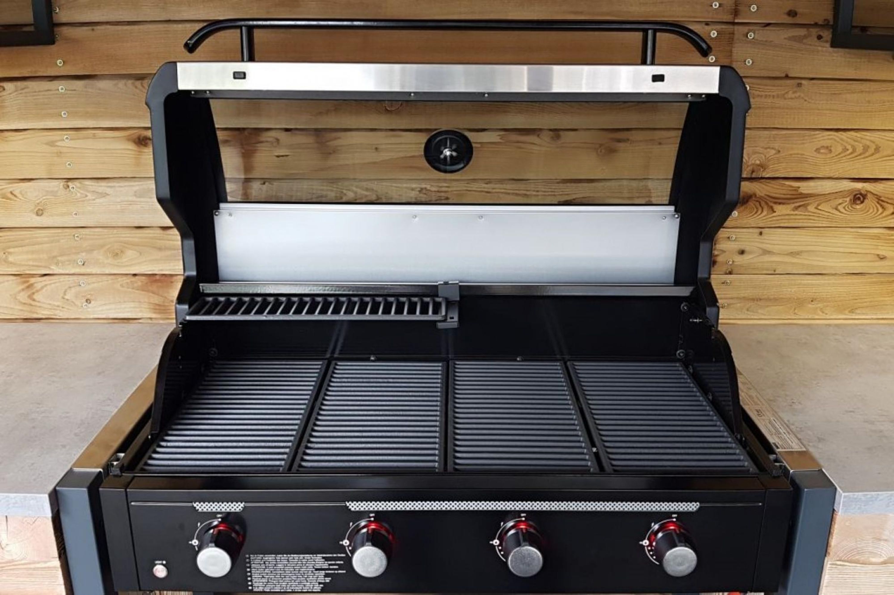 Ein tragbarer Grill mit Deckel aus Edelstahl und einer Bedieneinheit mit drei Drehreglern.