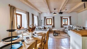 A spacious living room with a wooden ceiling, a sofa set, a dining table with a candle centerpiece, and a kitchen area with a wooden countertop. - Lucany nad Nisou - Lla560 (Lučany nad Nisou)