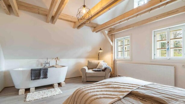 A bedroom with a large bed, a white bathtub, a chair, and a window. - Lucany nad Nisou - Lla560 (Lučany nad Nisou)