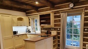 A kitchen with white cabinets, a wooden island, a sink, and a window with curtains. - Villa Horni Marsov - Khp120 (Horni Marsov)