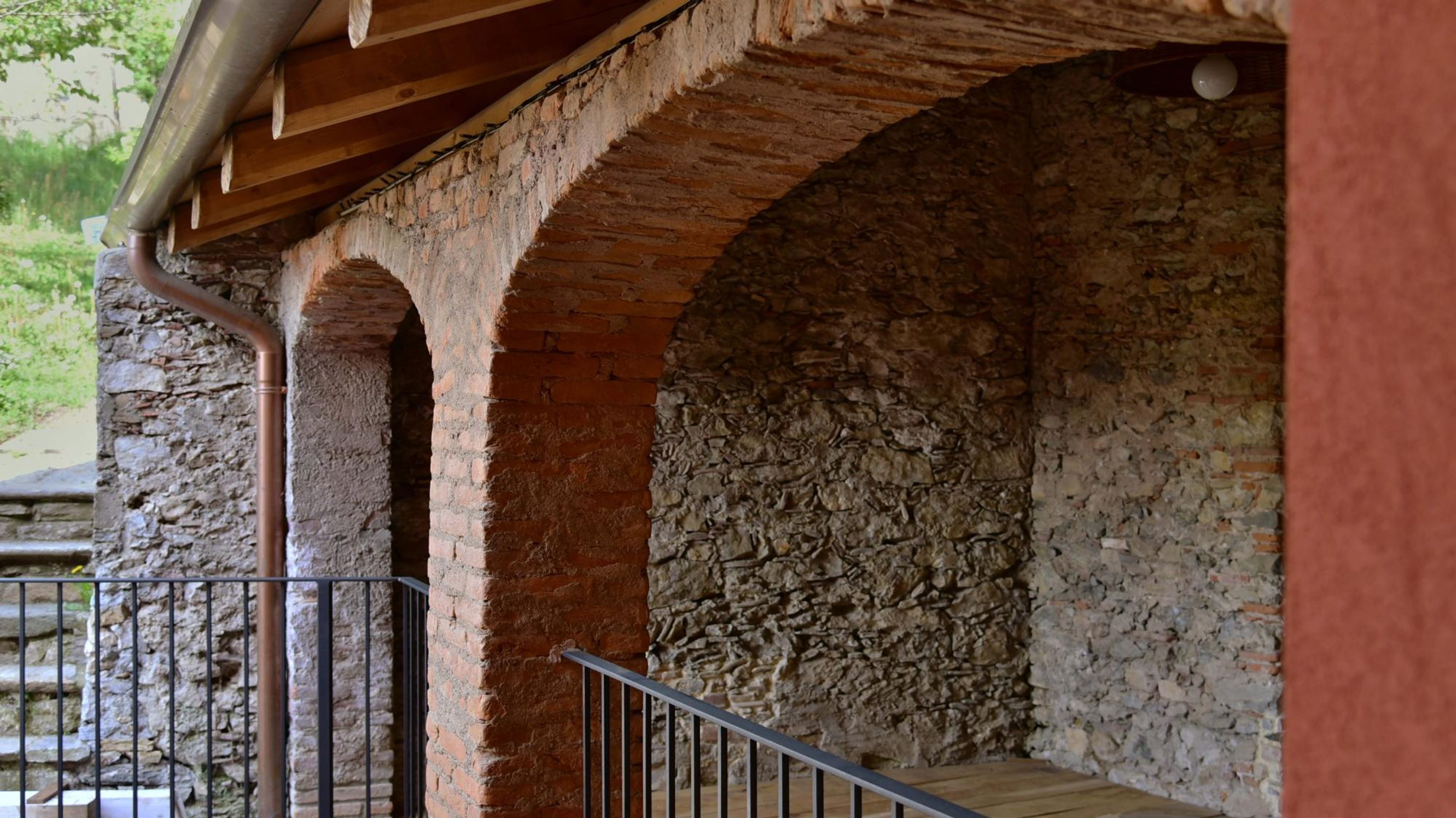 Un muro in pietra con una struttura di travi in legno sopra.