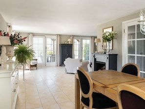 A spacious dining area with a wooden table and chairs, a fireplace, and a view through large windows.