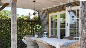 An outdoor patio with wicker furniture and a table set for dining. - Cozy cottage with heated pool, garden and covered terrace (Tzummarum)
