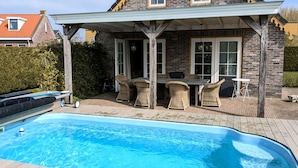 A house with a covered patio, a swimming pool, and outdoor furniture. - Cozy cottage with heated pool, garden and covered terrace (Tzummarum)