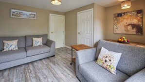 Ein Wohnzimmer mit zwei grauen Sofas, einem Holztisch und einem Gemälde an der Wand.