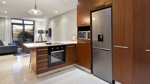 A modern kitchen with wooden cabinets, stainless steel appliances, and a large island. - Eden on the Bay 129 (Cape Town)