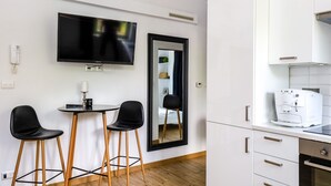 A modern kitchen with a built-in oven, a coffee machine, and a flat-screen TV mounted on the wall. - Old Town Szczecin Apartment (Szczecin)