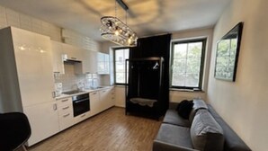 A modern kitchen with white cabinets, a black countertop, and a hanging light fixture. - Old Town Szczecin Apartment (Szczecin)