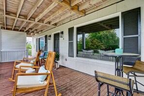 A covered outdoor area with wooden chairs and a table, large windows, and a view of greenery. - Coastal Getaway: Pet-Friendly, Across the street to the Beach (Wrightsville Beach)