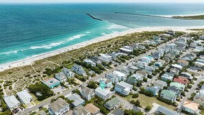 Vista aérea de una zona residencial costera con casas, una playa y un muelle.
