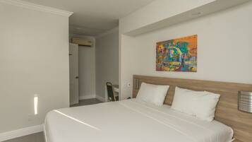 A bedroom with a large bed, a wooden headboard, and a colorful abstract painting on the wall.