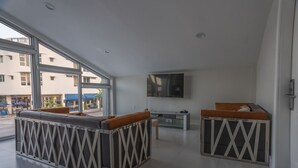 Ein modernes Hotelzimmer mit großem Fenster, Flachbildfernseher und einer Couch mit einem einzigartigen geometrischen Muster.