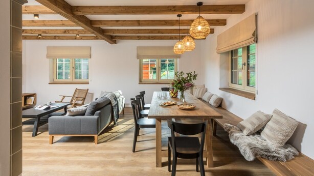 A spacious dining area with a wooden table and chairs, a sofa, and a window with a view of greenery. - Hutisko - Solanec Mha555 (Hutisko-Solanec)