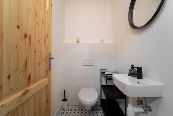 A small bathroom with a toilet, a sink, and a mirror.