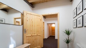 A hallway with a wooden door, a bench, a potted plant, and framed numbers on the wall. - Villa Desna - Lds021 (Desna)