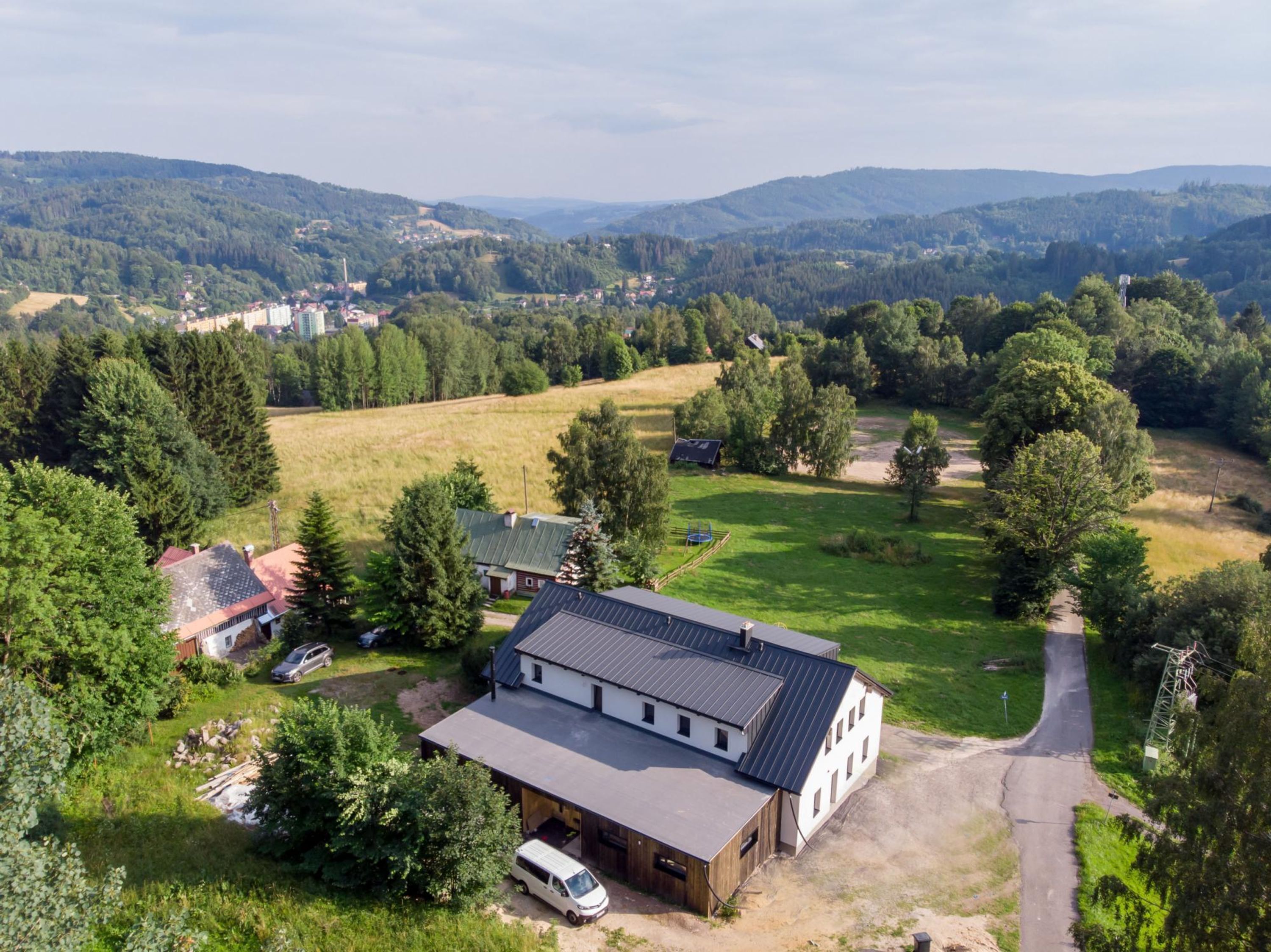 A rural property with a large barn, open fields, and a road leading to a village.