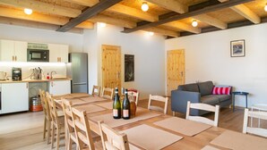 A modern kitchen with a built-in microwave and refrigerator, wooden dining table with chairs, and a cozy living area with a sofa and a framed picture on the wall. - Villa Desna - Lds021 (Desna)