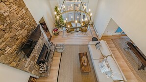 A spacious living area with a stone fireplace, a large chandelier, and a cozy seating arrangement. - Newly Renovated mountain top Ski House - Short Walk to Slopes (Somerset)