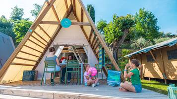 A wooden A-frame structure with a covered seating area, a table, and chairs.
