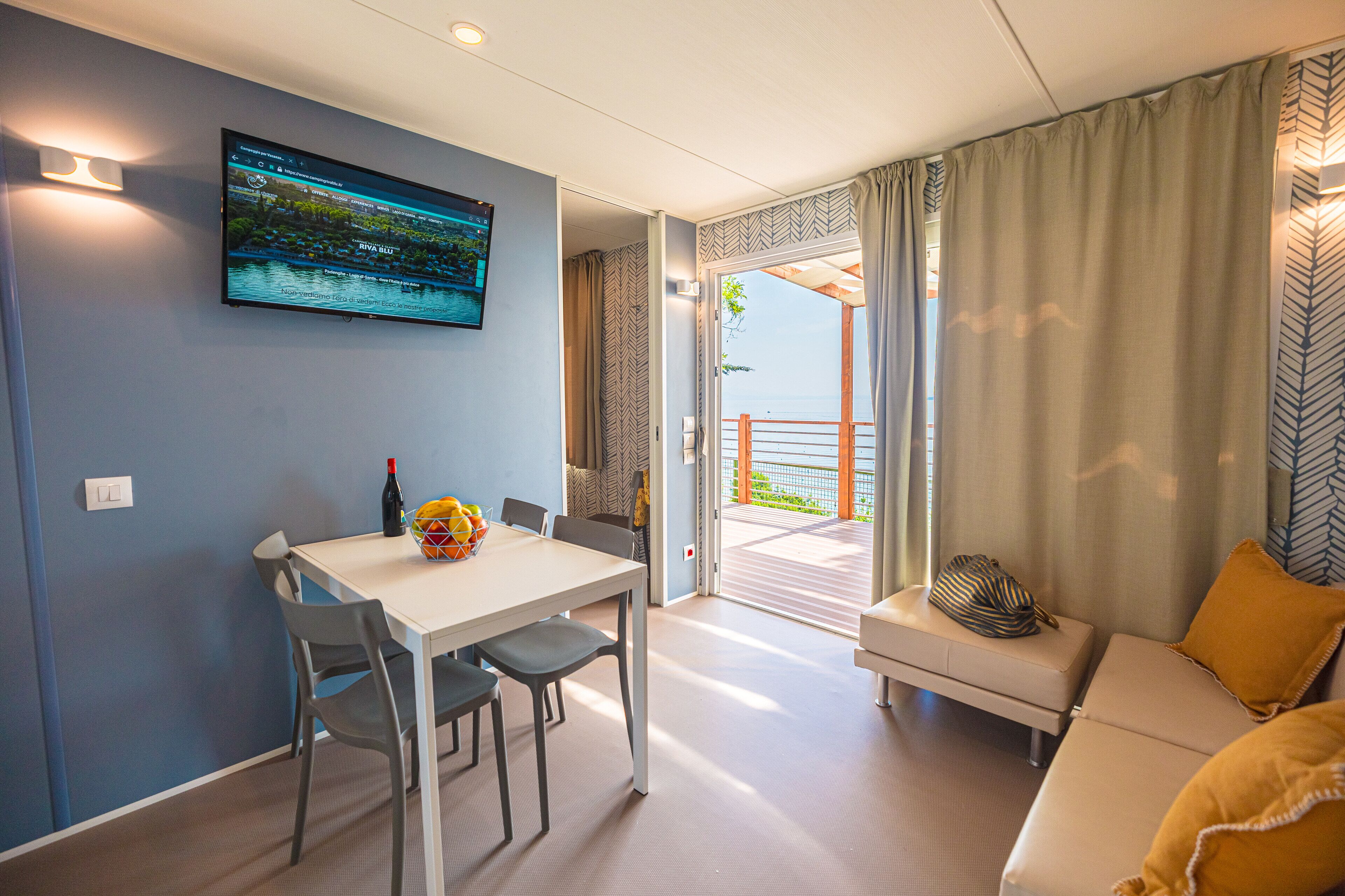 A modern room with a dining table, chairs, a sofa, and a TV mounted on the wall.
