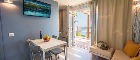 A modern room with a dining table, chairs, a sofa, and a TV mounted on the wall.